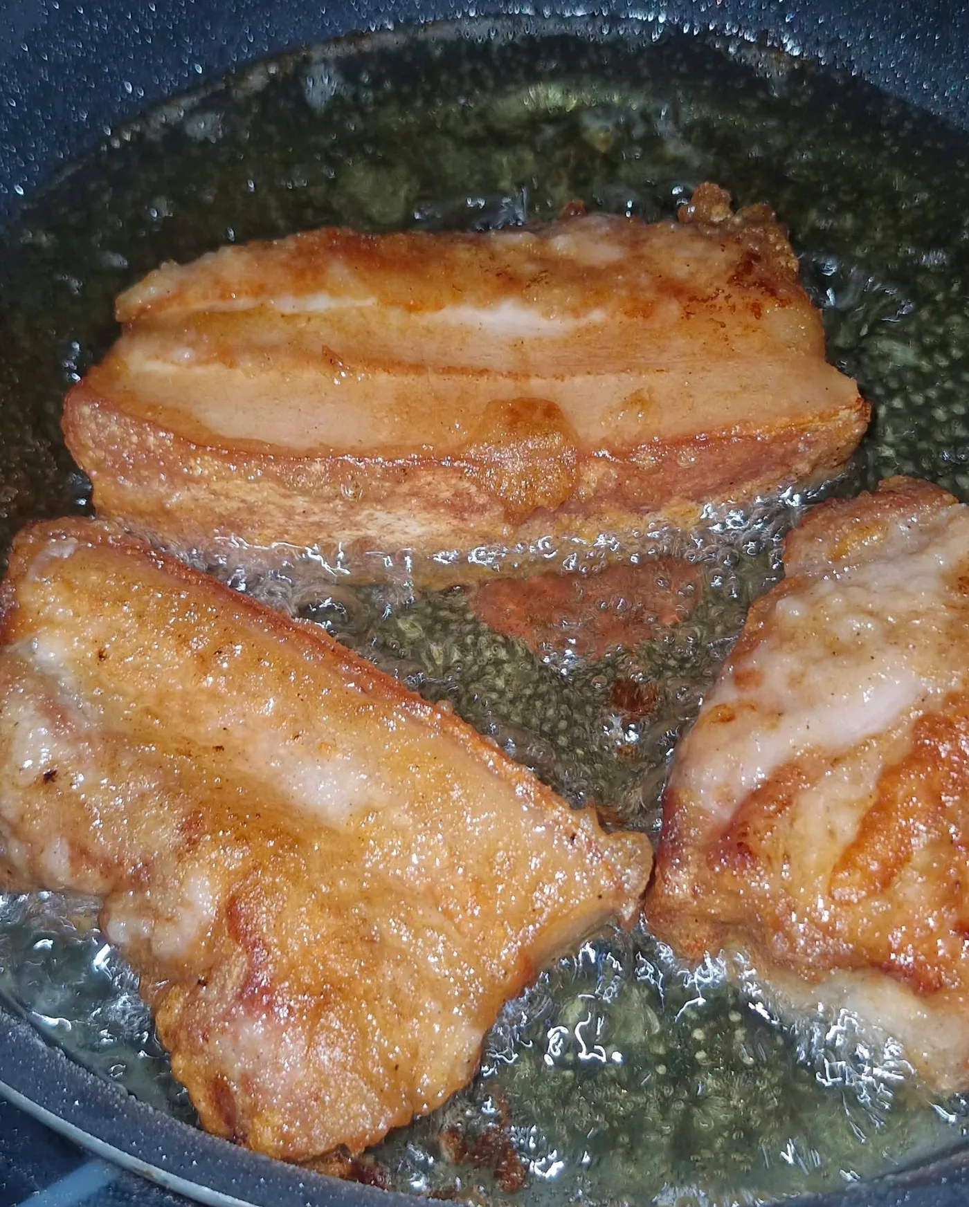 หมูสามชั้นกำลังทอดจนเหลืองในกระทะ