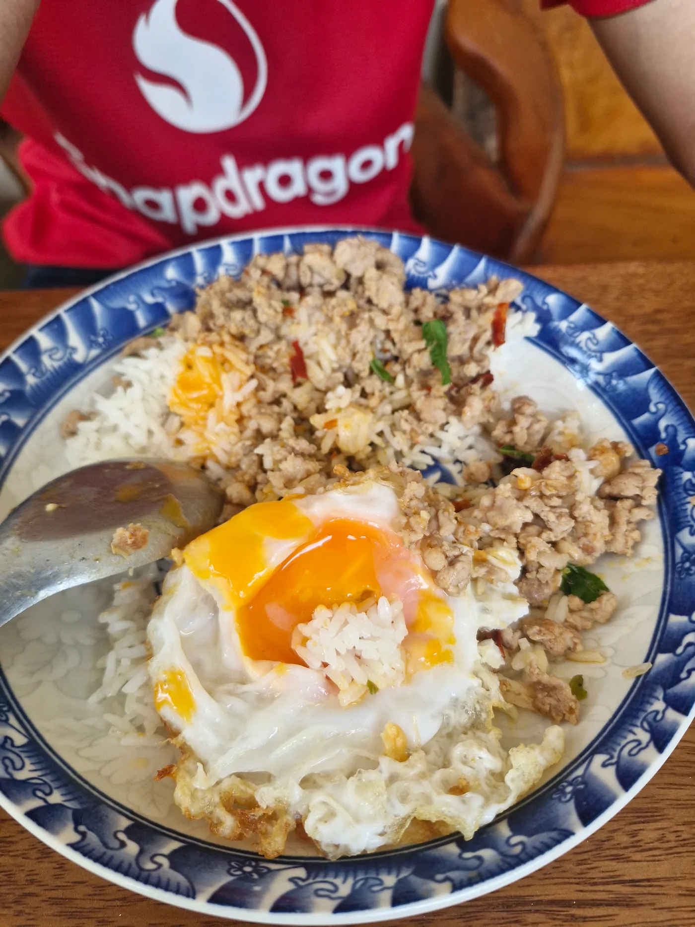 ข้าวกะเพราหมูสับกับไข่ดาวบนจานลายสีน้ำเงิน